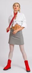 stylish blonde woman in a white shirt, red tie and boots. front view. full length