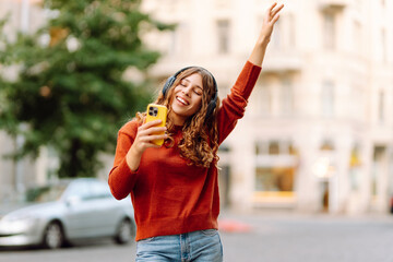 Young woman listening music while walking in the street. Travel, tourism, technology, blogging concept