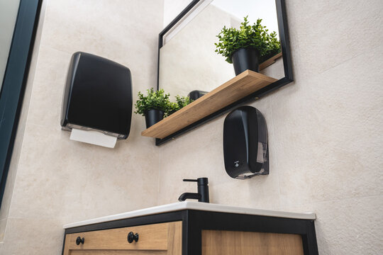 Black dispenser for electronic liquid soap and black dispenser for paper towels in a luxury bathroom.Bottom view.