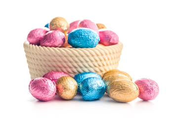 Chocolate easter eggs wrapped in multi colored foil in bowl isolated on white background.