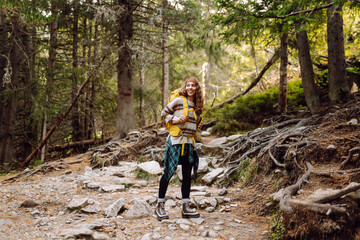 Smiling hiker using smartphone in forest.  Female tourist using mobile internet in woods. Blogging....