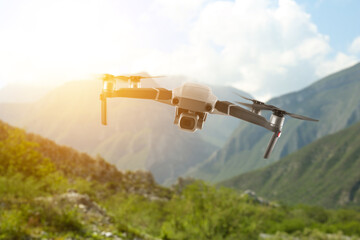 Drone with camera flying in mountains. Unmanned aerial vehicle for surveillance