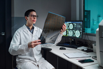 Scientist wearing lab coat examining an X-ray image in a medical laboratory. Computer screen...