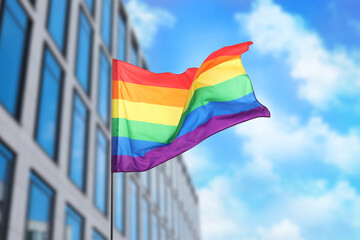 LGBT flag fluttering against building outdoors, low angle view