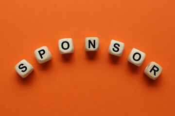 Word Sponsor made of wooden cubes with letters on dark orange background, top view
