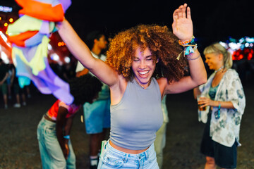 Young woman dancing and waving a colorful scarf at a music festival at night
