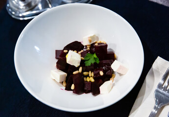 Vegan dish of boiled beetroot slices with tofu cheese and pine nuts