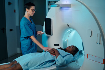 Medical technician conducting MRI scan for patient in hospital setting, ensuring accurate...