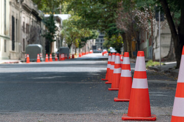 Orange and white traffic cones lining an empty city street, creating a barrier for vehicles