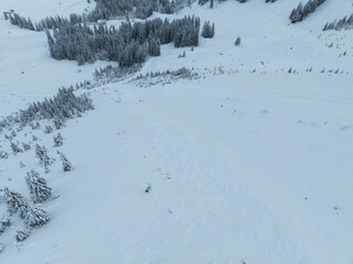 Aerial view of snowy mountain slope. Texture of snow surface from above.