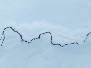 Aerial view of meandering through snowy landscape in Switzerland.