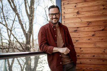 Smiling man leaning on balcony railing enjoying view
