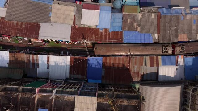 Aerial view of busy Maeklong Railway Market with market stalls, Thailand. Aerial drone video