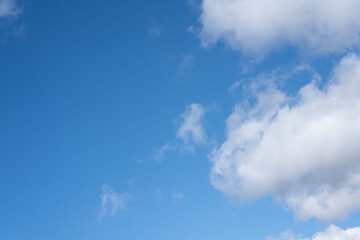 vast blue sky with fluffy white clouds scattered across, creating a serene and tranquil atmosphere, invoking a sense of calmness and freedom in the open expanse above, refreshing, gentle, sunny