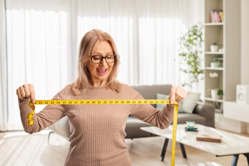 Excited middle aged woman holding a measure tape