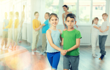 Young children couple learns to quickstep pair dance during dance class in studio, repeat movements...