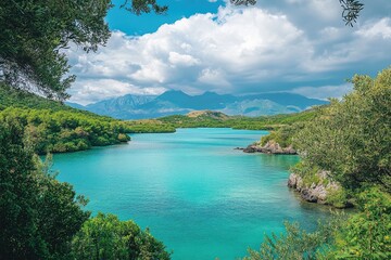 Serene turquoise bay nestled amidst lush greenery and majestic mountains under a partly cloudy sky.