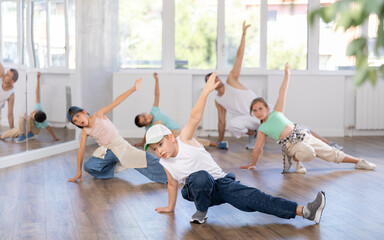 Portrait of active teen boy enjoying modern energetic dancing in group at street dance studio