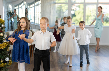 Christmas ball - group of children in festive clothes dances a waltz around the New Year tree