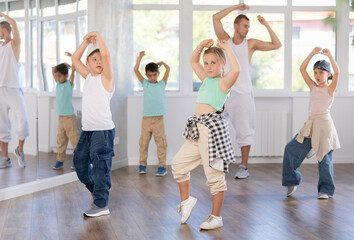 Fototapeta premium Dance group of children in casual clothes are training together to dance hip-hop and breakdancing in a dance center
