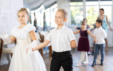 Group of cheerful emotional tweens, girls ad boys in formal wear dancing slow romantic partner...