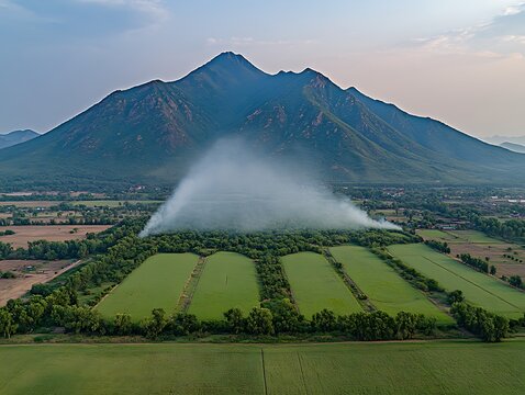 A dramatic mountain landscape with agricultural fields and smoke