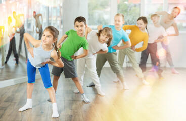 Naklejka premium Happy smiling preteen dancers practicing dance routine with female choreographer in modern studio