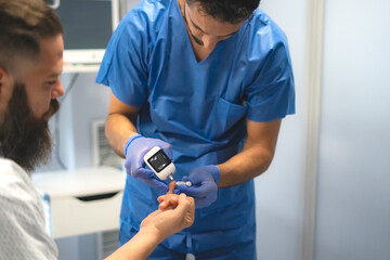 Doctor measuring patient's blood glucose level with glucometer in hospital room