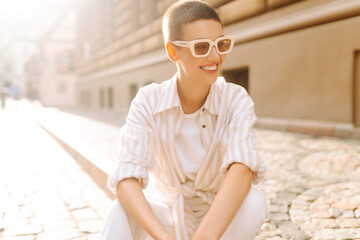 Portrait of pretty woman with short hair sitting on the street stairs. Fashion style. Urban life.