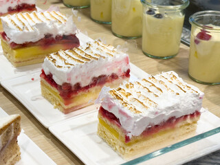 Delicious raspberry meringue cake slices on display in a bakery setting