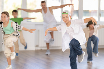 Active children practicing hip-hop dance in training hall during group dancing classes