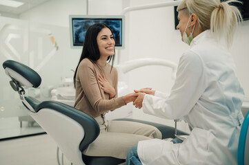 Female dentist reassuring patient before dental procedure in modern clinic