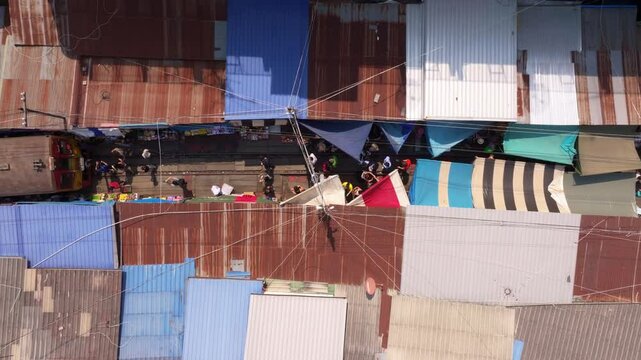 Aerial shot of Maeklong Market, train tracks, and local stalls, Thailand. Aerial drone video
