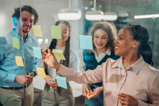 Business team brainstorming and planning using sticky notes on glass wall
