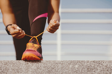 Start of day and workout. African american girl with fitness tracker in trendy sportswear tying...