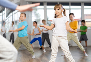 During dance workshop, girl with team of young like-minded children learn to dance modern dances,...