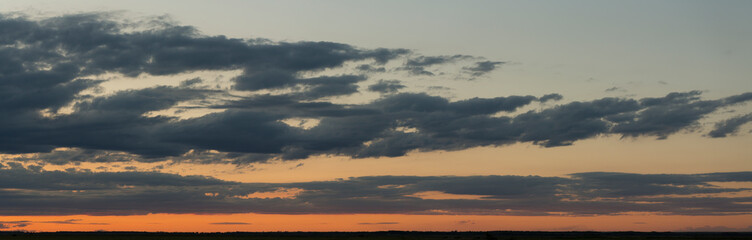 Landscape at sunset. Tragic gloomy sky. Panorama. Crimson twilight. Heavy, gloomy, dark clouds.