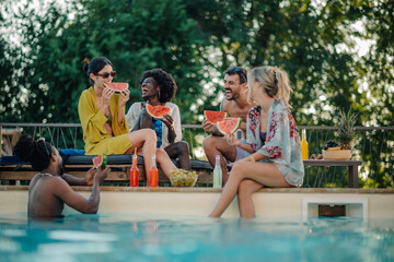Obraz premium Friends eating watermelon by the poolside during summer vacation