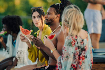 Friends eating watermelon slices at poolside party