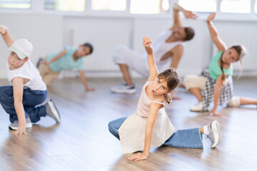 Obraz premium Cheerful sports preteen girls and boys hip hop dancers doing dance workout on floor with male trainer during group class at dance studio