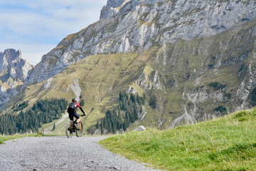 a cyclist rides along a mountain road in the Alpine mountains