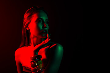 Portrait of a young woman in colorful neon lighting, red and green hues, expressing elegance, charm