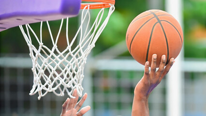  A basketball poised for a shot, the net awaiting its arrival.The hand, focused and determined, guides the ball toward the hoop.