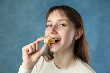 Beautiful woman eating tasty mochi on blurred blue background