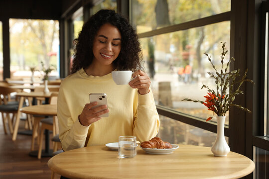 Woman using smartphone during her coffee break in cafe