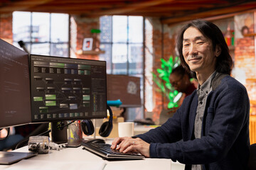 Portrait of happy CTO manager using PC in startup office to design and implementing algorithms...