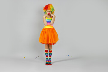 Cute girl dressed like clown on grey background. Surprise party
