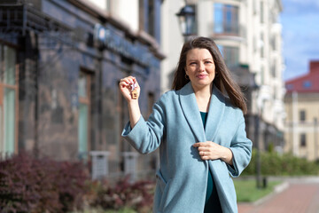 beautiful young pregnant woman with keys to house, apartment outdoors. purchase of real estate. maternity capital. female owner of new flat, home . mortgage, real estate installment plan.