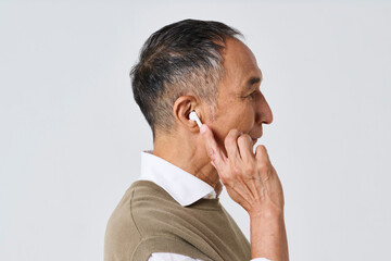 ワイヤレスイヤホンを使う私服姿のシニア男性