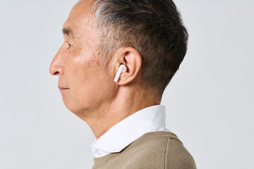 Fototapeta premium ワイヤレスイヤホンを使う私服姿のシニア男性